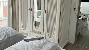 A hotel room with a bed, a wardrobe, a mirror, and a view of the outdoors. - für 2 Personen  + 4 Kinder ca. 52 m² in Norderney, Norddeutschland (Nieder by Interhome (Norderney)