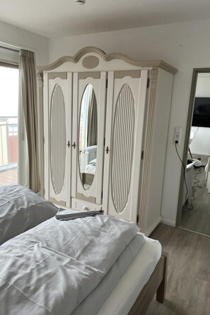Ein Hotelzimmer mit Bett, Kleiderschrank, Spiegel und Blick ins Freie.