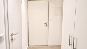 A hallway with a wooden floor, white walls, and a closed door at the end. - für 2 Personen  + 4 Kinder ca. 52 m² in Norderney, Norddeutschland (Nieder by Interhome (Norderney)