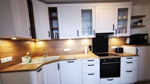 A modern kitchen with white cabinets, a wooden countertop, a sink, a dishwasher, and a black oven. - für 2 Personen  + 4 Kinder ca. 52 m² in Norderney, Norddeutschland (Nieder by Interhome (Norderney)