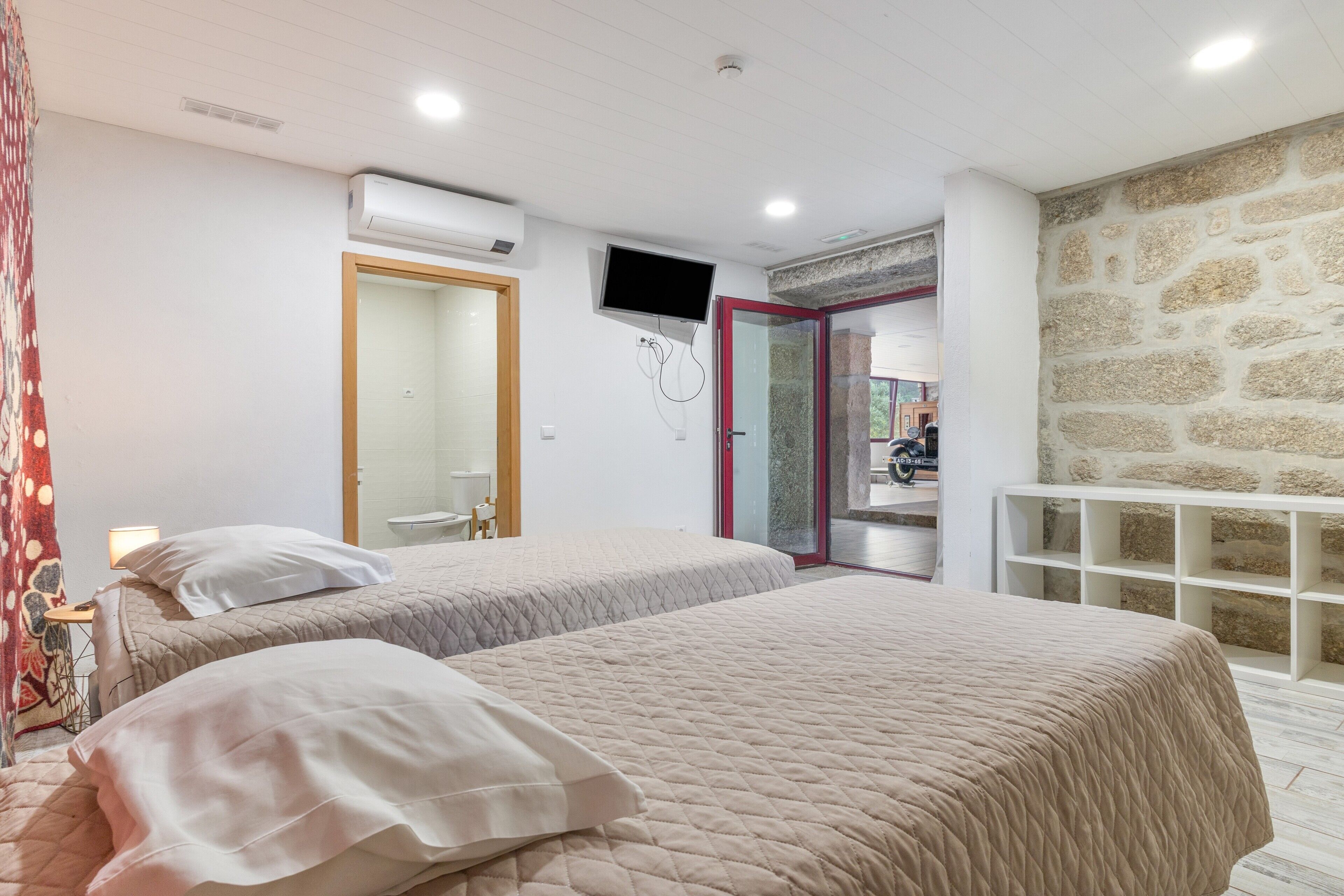 Una camera da letto con due letti, una TV e un muro in pietra.