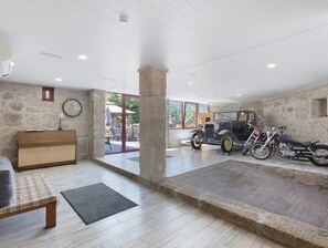 A spacious room with a stone wall, a wooden bench, a small table, and a motorcycle.