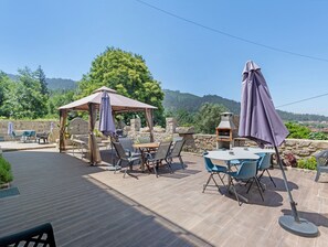 Une terrasse extĂ©rieure dotĂ©e dâun belvĂ©dĂšre, de tables, de chaises et dâun barbecue.