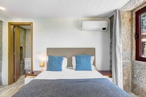 Ein Hotelzimmer mit Bett, Nachttisch, Lampe, Klimaanlage und Blick ins Freie.