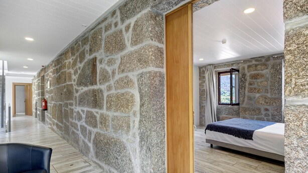 A room with stone walls, a bed, a wooden door, and a window. - Room 'Room 14 - Quinta Do Avô' with Mountain View, Wi-Fi and Air Conditioning (Ribeira)