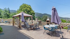 Eine Außenpatio mit Gazebo, Tischen, Stühlen und einem Grill.