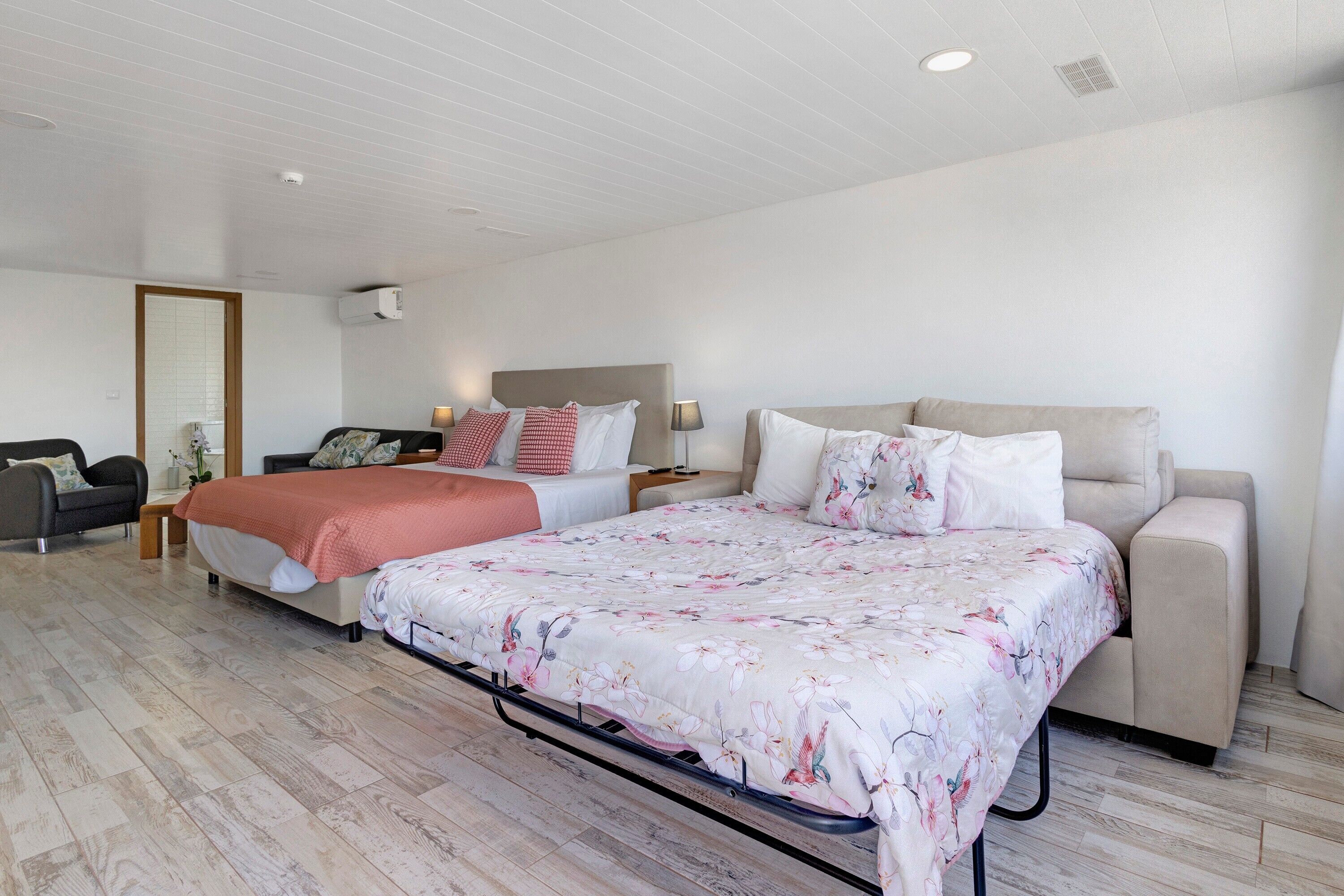 Ein modernes Hotelzimmer mit einem großen Bett, einer Couch, einem Schreibtisch und einem Sessel.