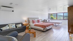 Ein modernes Schlafzimmer mit einem großen Bett, einer Couch und Blick ins Freie.