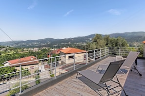 Un balcón con vistas a un pueblo, una barandilla y dos sillones de relax.