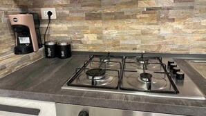 A kitchen with a gas stove, a coffee maker, and salt and sugar containers on the counter.