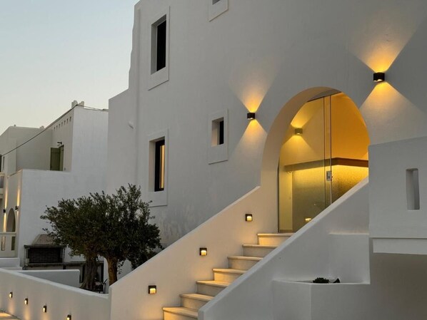 Un edificio moderno con paredes blancas, una escalera y varios ventanales pequeños.