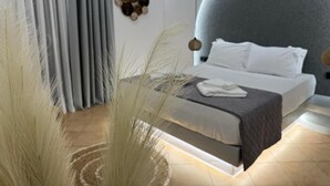 Ein modernes Schlafzimmer mit Bett, Vorhängen, einem Wandkunstwerk und einer ungewöhnlichen, kugelförmigen Decke.