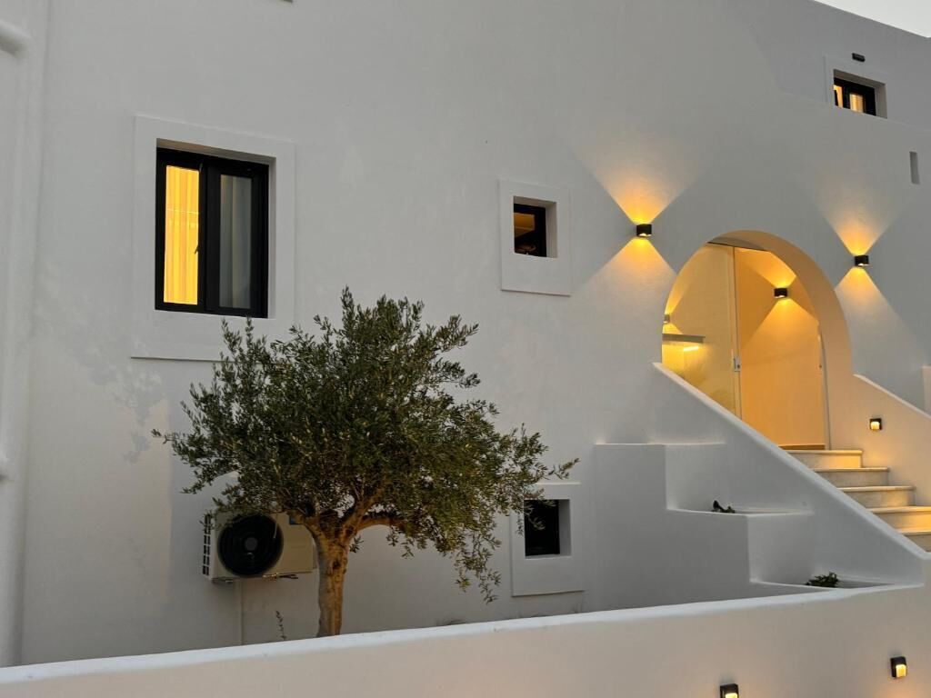 Un bâtiment moderne avec un escalier, un arbre et des lampes fixées au mur.