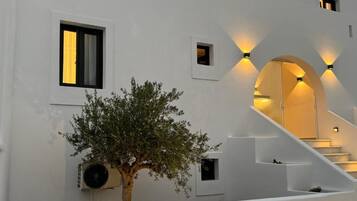 Un bâtiment moderne avec un escalier, un arbre et des lampes fixées au mur.