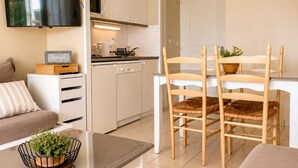 Una cucina moderna con mobili bianchi, una televisione a schermo piatto, un tavolo da pranzo con sedie e un piccolo vaso con una pianta.