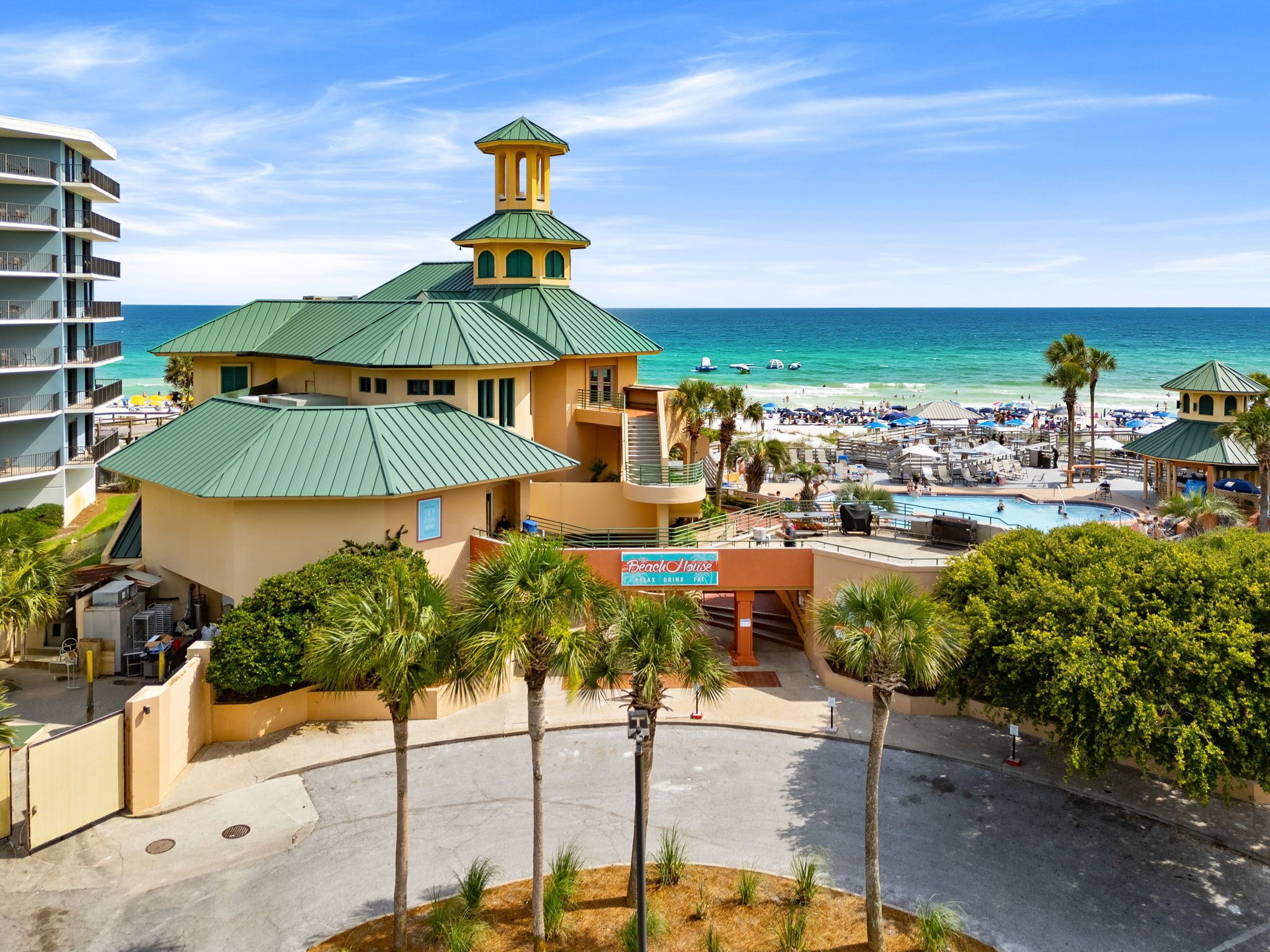 A resort with a pool, beach, and a building with a green roof.