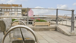 A waterfront promenade with benches, a pink building, and a row of terraced houses. - Flat 30 (Bridport)