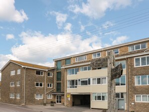 A multi-story building with a sign indicating a coastal path and a nearby harbour. - Flat 30 (Bridport)