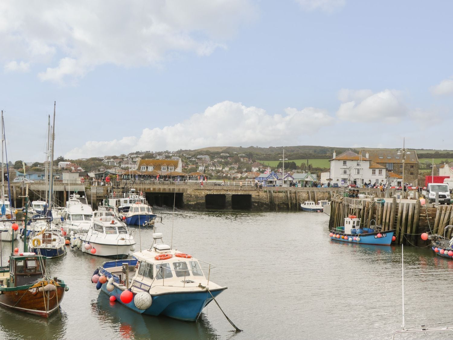 A harbor with boats docked, a bridge, and buildings in the background.