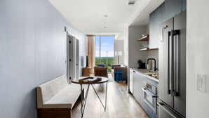 Eine moderne Küche mit einem großen Kühlschrank, eine Essecke mit einer Bank und einem Tisch sowie ein Blick auf Grünflächen.