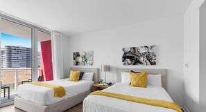 A hotel room with two beds, a balcony, and artwork on the walls. - 2BR South Florida - Beach Access - Private Balcony (Hallandale Beach)