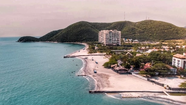 Zona costera con playa, muelle y un edificio de varios pisos.