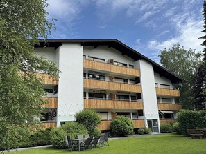 A multi-story building with balconies, a lawn, and outdoor seating.