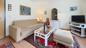 Una sala de estar con sofá, mesa de centro, mueble para televisión y objetos decorativos.
