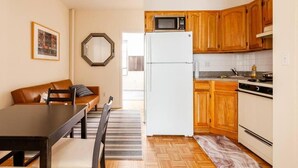 Cocina compacta con armarios de madera, refrigerador, microondas y estufa.