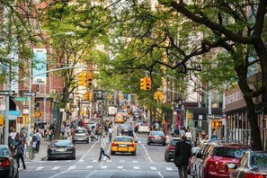 Una calle urbana concurrida, peatones, automóviles y semáforos.