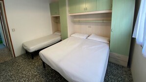 A bedroom with two single beds, a green wardrobe, and a hanging light fixture. - Ground Floor Apartment Near Beach (San Michele al Tagliamento)