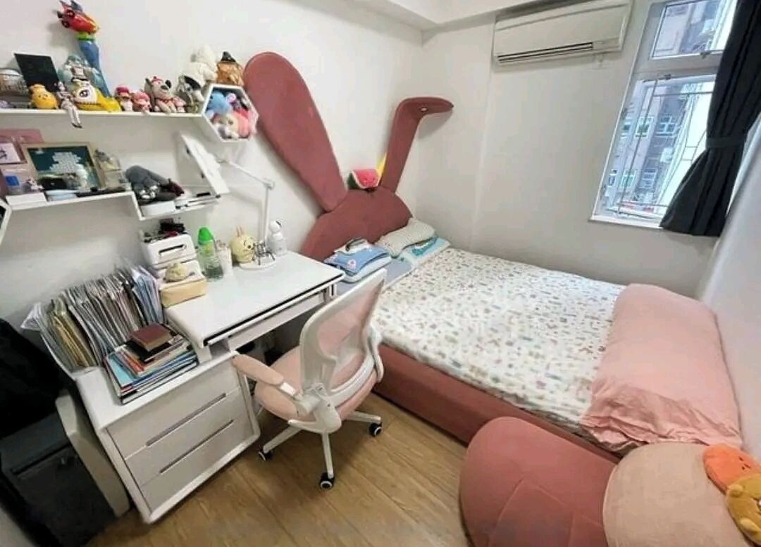 A bedroom with a desk, chair, bed, and shelves with various items.