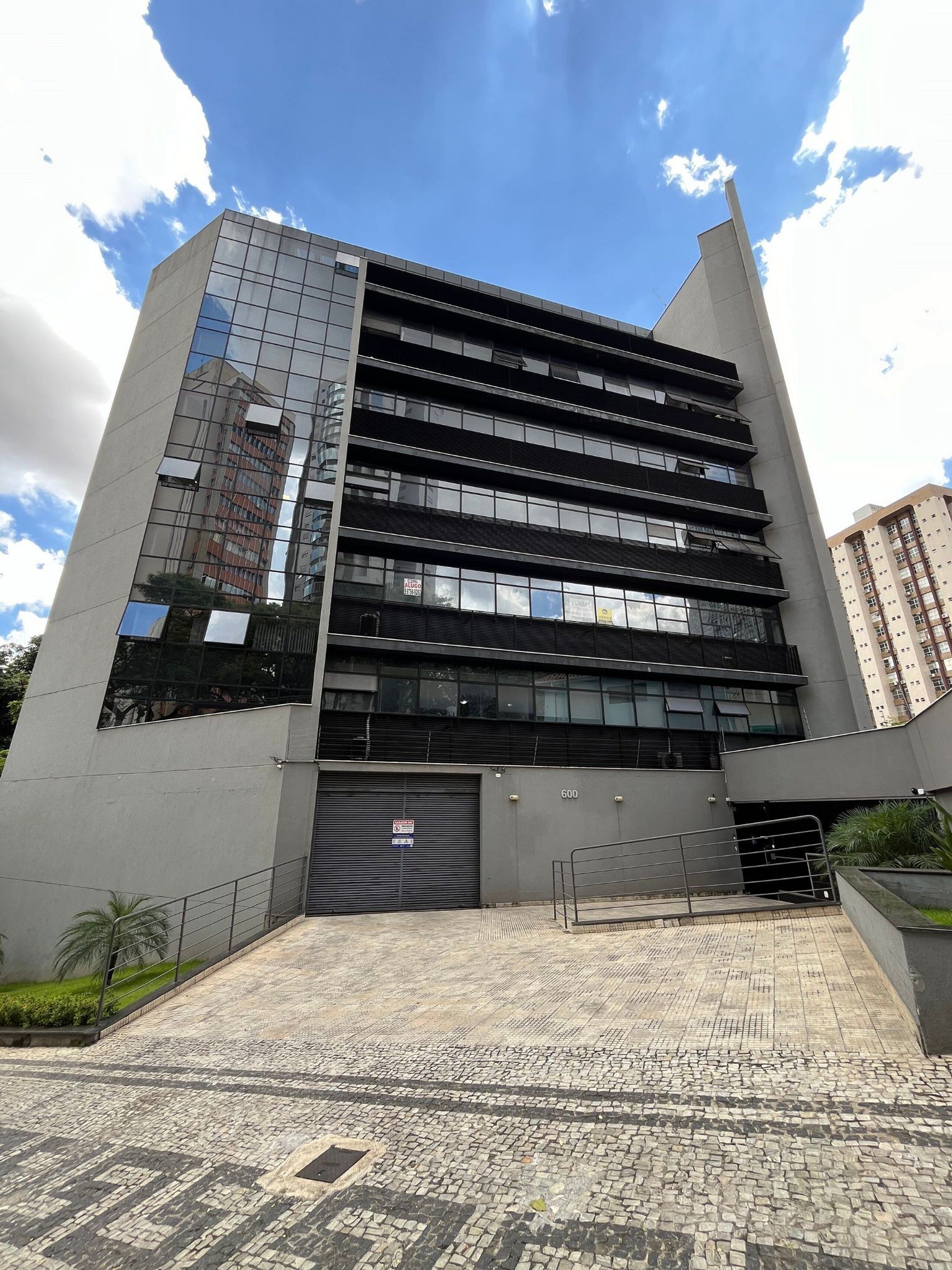 A modern building with multiple floors, large windows, and a gated entrance.