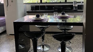 Una cocina con un ventanal grande, un refrigerador, una cafetera y dos taburetes de bar.