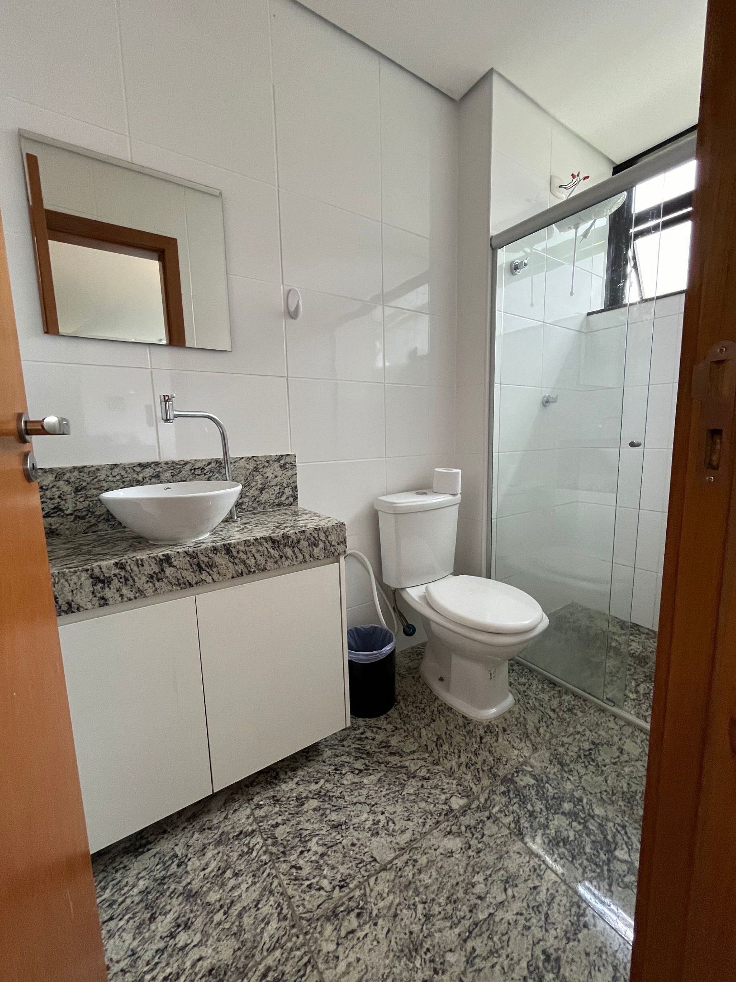 Casa de banho com lavatório, sanita e chuveiro.
