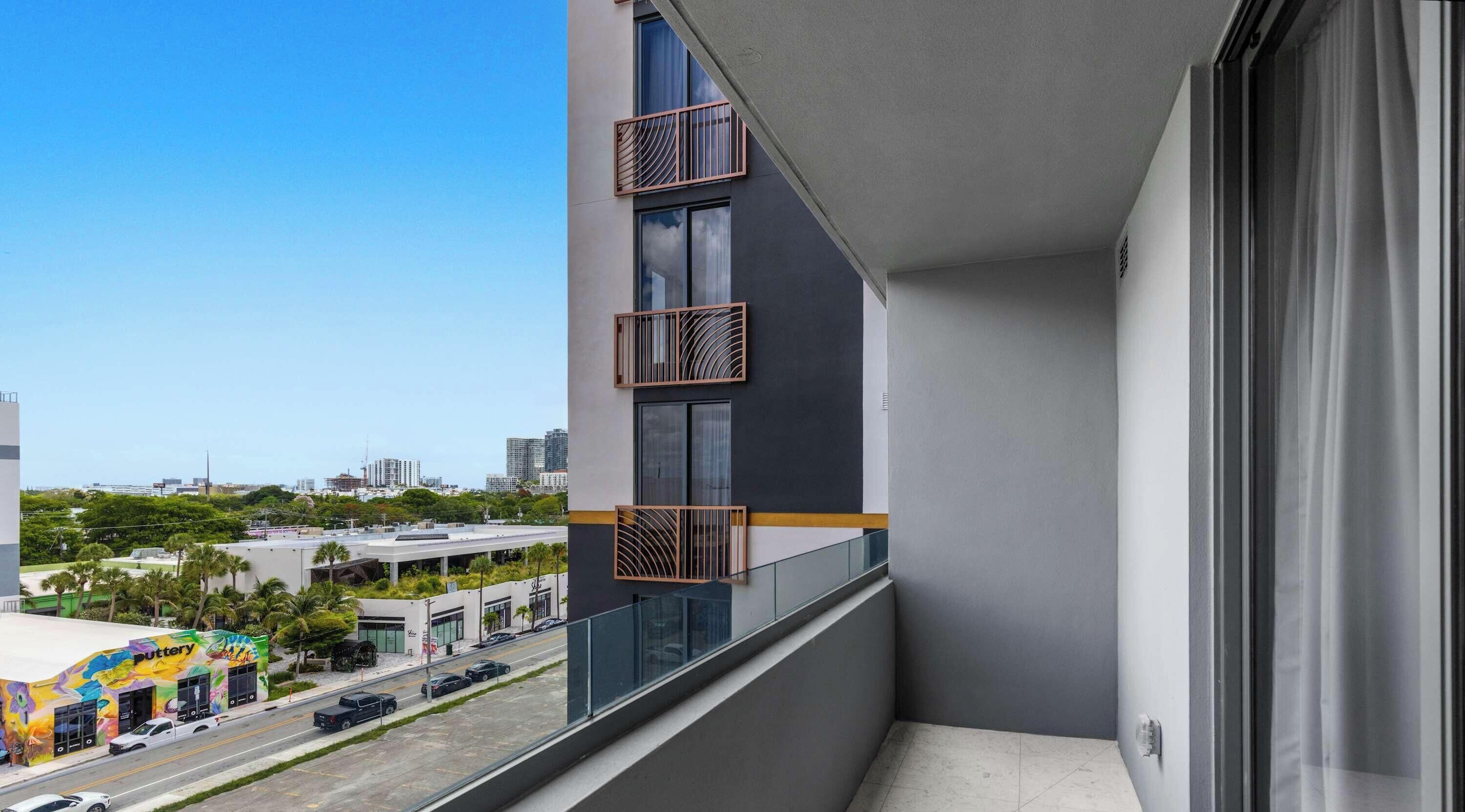 Un balcón con vista a la ciudad, fachada de edificio moderna y cielo despejado.