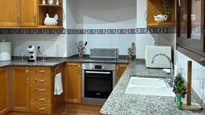 A kitchen with wooden cabinets, a built-in oven, granite countertops, and a window with a view.