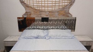 Un lit avec une couvre-lit à motifs, une tête de lit à motifs géométriques et une table de chevet avec une lampe.