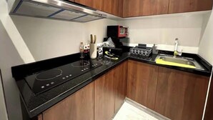 A compact kitchen with wooden cabinets, a black countertop, a built-in microwave, and a sink. - Well located apartment, in the heart of the best Col. Roma and Col. Countess (Ciudad de México)