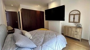 A bedroom with a bed, a TV mounted on the wall, a wardrobe, and a cabinet. - Well located apartment, in the heart of the best Col. Roma and Col. Countess (Ciudad de México)