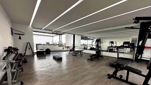 A spacious gym with various exercise equipment, a mirrored wall, and a wooden floor. - Well located apartment, in the heart of the best Col. Roma and Col. Countess (Ciudad de México)