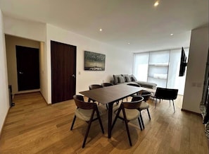 Ein modernes Wohnzimmer mit Esstisch, Sofa und Sesseln.