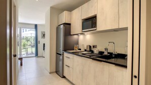 Eine moderne Küche mit einem Edelstahlkühlschrank, einer Mikrowelle und einem Spülbecken mit Armatur.
