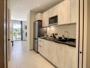 A modern kitchen with a stainless steel refrigerator, a microwave, and a sink with a faucet. - Apartment  by Interhome (Cannes)