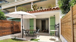Eine Terrasse mit Tisch und Stühlen, ein Holzzaun und eine Kakteepflanze.