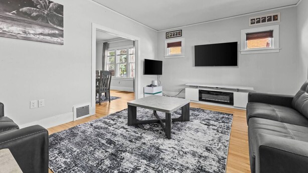 Un salon moderne doté d’un téléviseur à écran plat, d’un coin repas avec une table et des chaises, et d’une grande fenêtre offrant une vue sur l’extérieur.