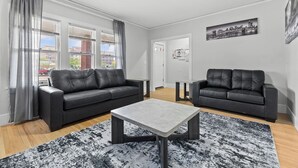 Un salon moderne avec deux canapés en cuir noir, une table basse grise et un tapis noir et blanc.
