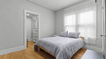 A bedroom with a bed, a wardrobe, a door, and a window with blinds.