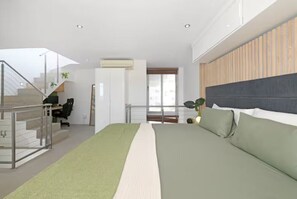 A modern bedroom with a large bed, a staircase, a desk, and a view of the outside. - Serene Penthouse with Iconic Views + Private Pool (Cape Town)