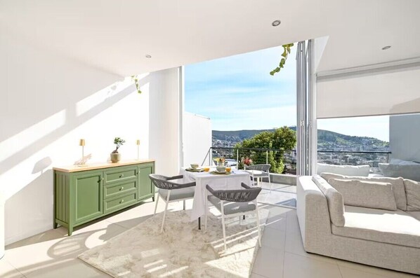 A modern balcony with a dining area, a sofa, and a view of the city.